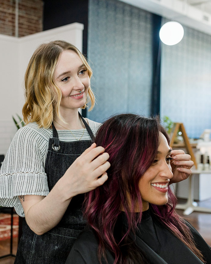 Kundin und Friseurin lächeln beim Styling einer Frisur zum Ausbildungsstart Friseur 2025