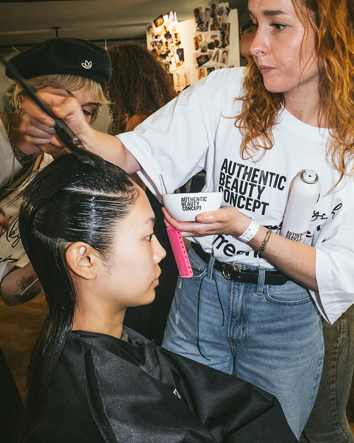 Behind the scenes foto von der Paris Fashion Week. Friseurin bestreicht Haare für ein Hair Look Tutorial