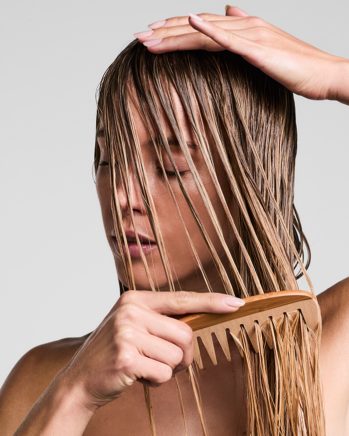 Model kämmt ihre nassen Haare mit einem Kamm mit der Clear Pflege von Paul Mitchell für empfindliche Kopfhaut